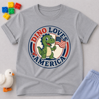 Dino Loves America Shirt Christian kids shirt in gray featuring a dinosaur holding an American flag
