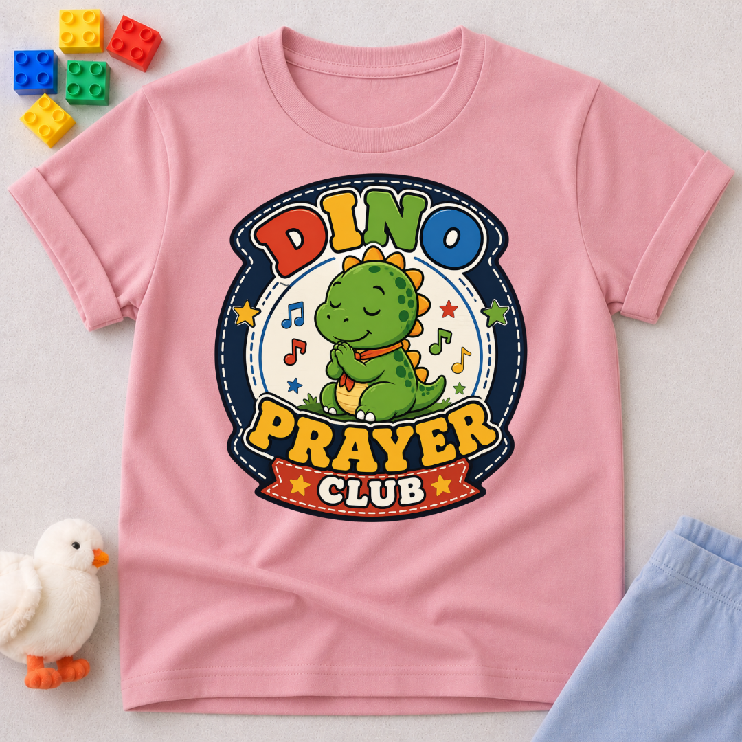 Dino Prayer Club Christian kids shirt in pink featuring a praying dinosaur with colorful lettering

