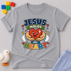 Jesus Holds My Heart Christian kids shirt in gray featuring a smiling heart with faith-inspired typography
