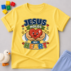 Jesus Holds My Heart Christian kids shirt in yellow featuring a smiling heart with faith-inspired typography
