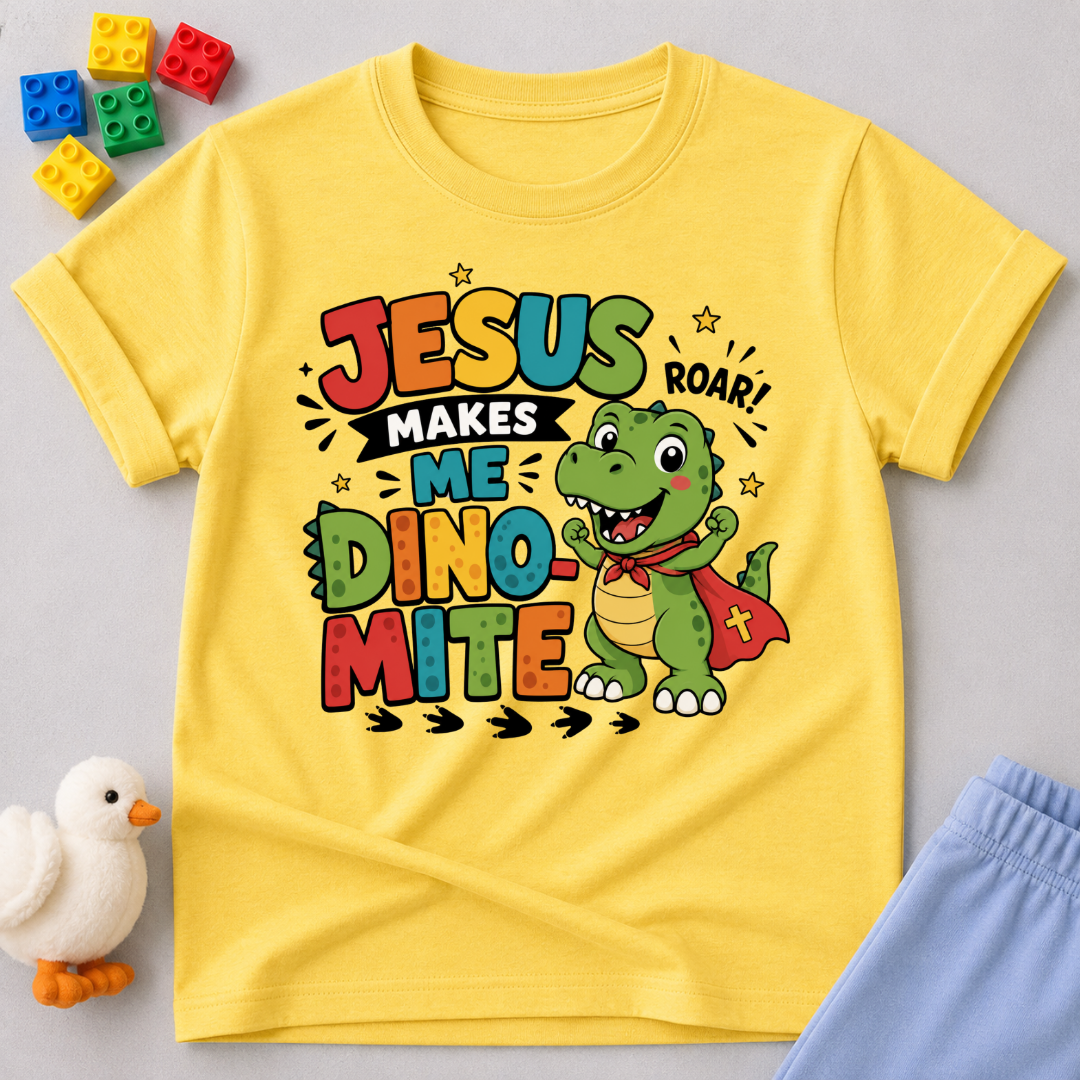 Jesus Makes Me Dino-Mite Christian kids shirt in yellow featuring a smiling dinosaur with a cape

