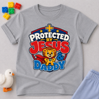 Protected by Jesus & Daddy Christian kids shirt in gray featuring a brave lion inside a protective shield
