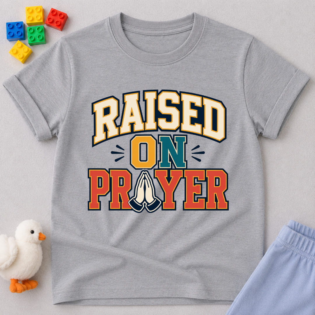 Raised on Prayer Christian kids shirt in gray featuring bold typography and praying hands
