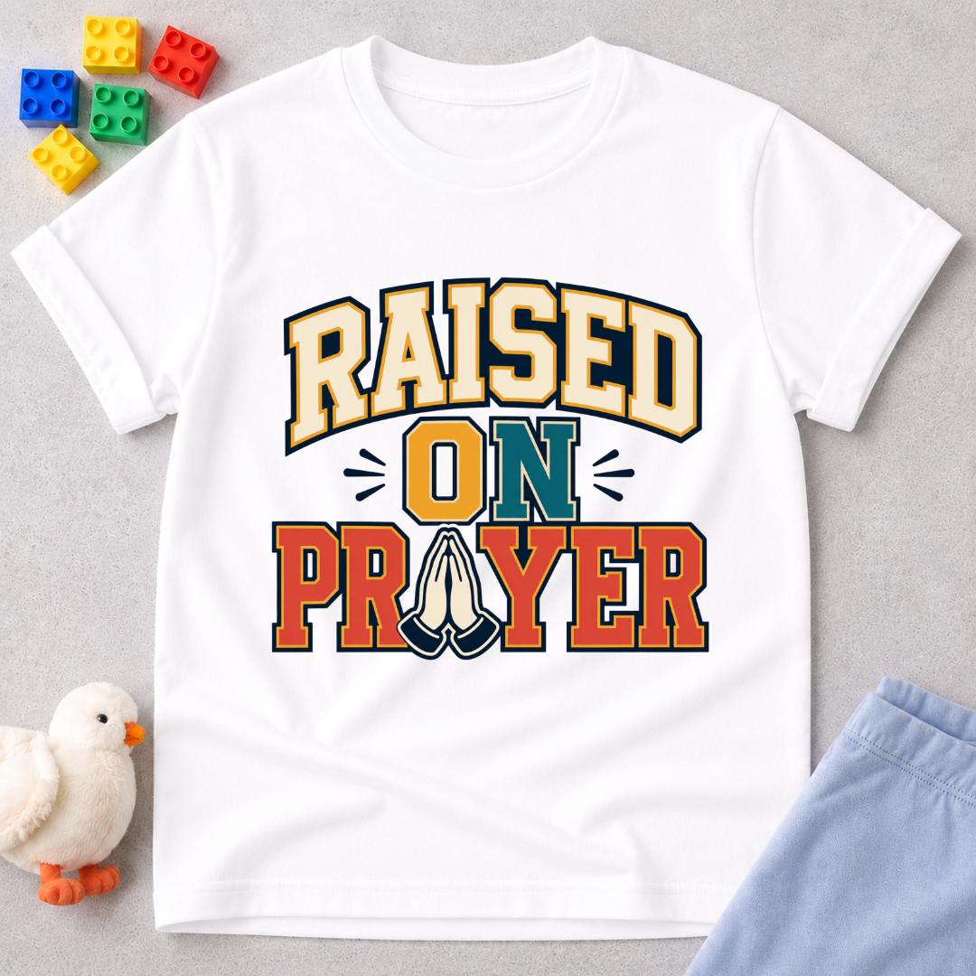 Raised on Prayer Christian kids shirt in white featuring bold typography and praying hands
