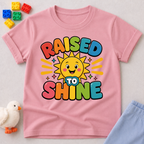Raised to Shine Christian kids shirt in pink featuring a smiling sunshine with colorful uplifting typography
