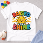 Raised to Shine Christian kids shirt in white featuring a smiling sunshine with colorful uplifting typography

