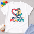 Raised with Love and Prayer Christian kids shirt in white featuring praying hands and heart artwork
